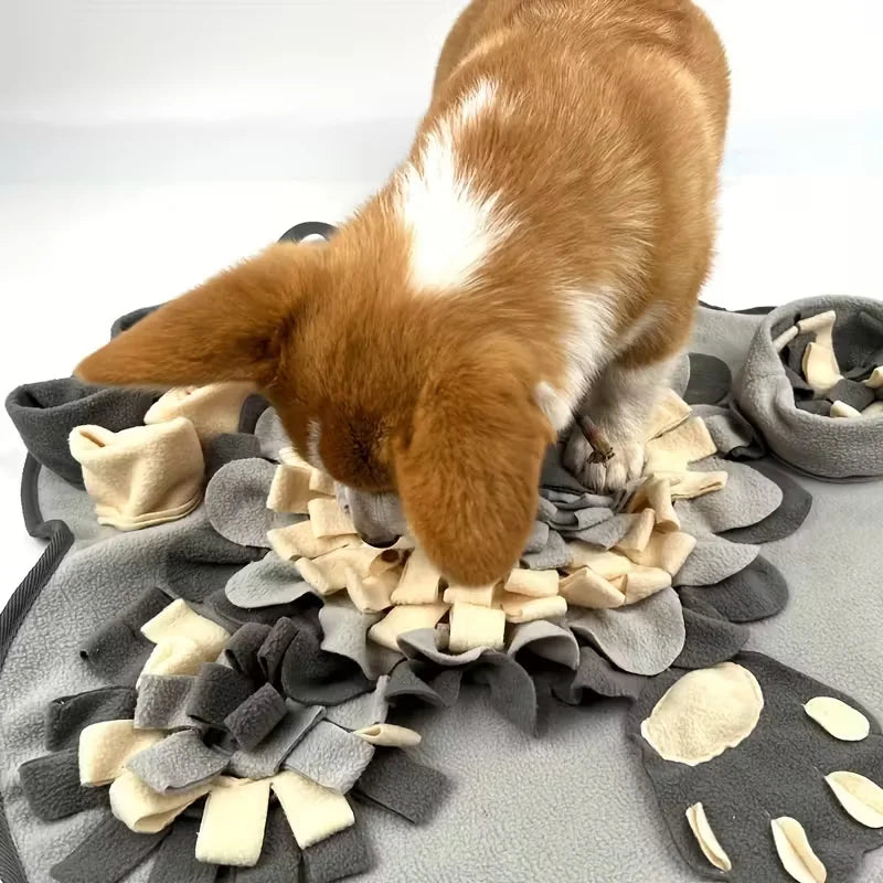 Brown and white dog nosing through a gray flower-shaped fleece snuffle mat