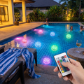 Colorful submersible LED lights glowing underwater in a pool with a handheld remote